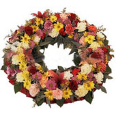 Mixed Flowers Wreath; A wreath with seasonal flowers and greens to convey your heartfelt meesage for a funeral/ sad occasion.